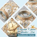 Two clear glass nautical lanterns with jute rope handles and flickering LED candles inside, on a tabletop.