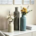 Set of three CUCUMI ceramic vases in distressed morandi colors, displayed on a shelf, showcasing rustic and coastal style.