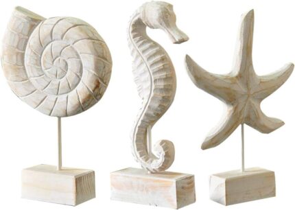 Set of three white hand-carved wooden coastal figurines: a starfish, a conch shell, and a seahorse, displayed on a tabletop.