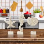 Set of three white hand-carved wooden coastal figurines: a starfish, a conch shell, and a seahorse, displayed on a tabletop.
