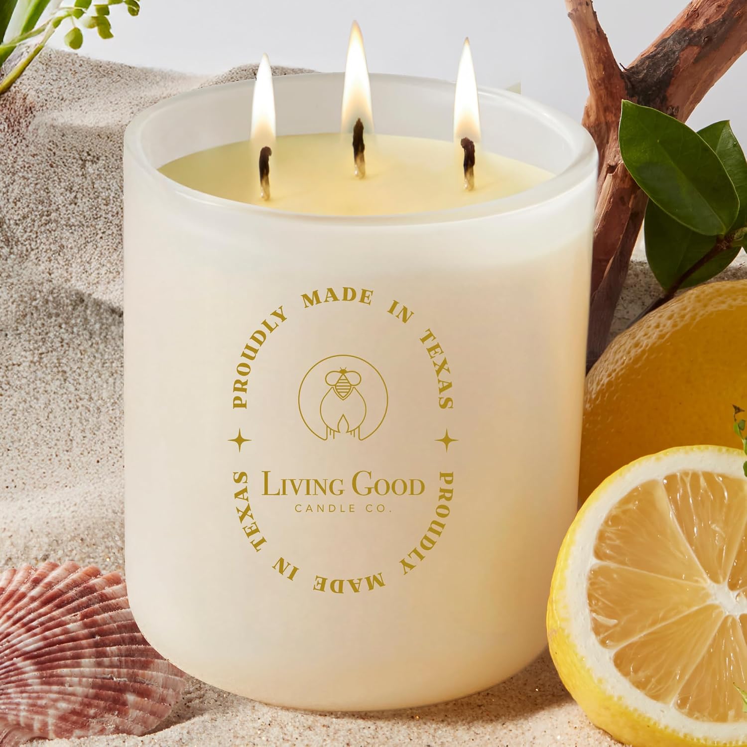 living-good-candle-co-coastal-breeze-yuzu-sea-salt-pure-beeswax-candle-90-hour-burn-15-oz-01 A warm yellow beeswax candle in a clear glass jar with three wicks, set against a light background.