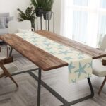 A Muktoujaumai blue starfish burlap table runner, 13x72 inches, laid flat on a dining table, showcasing its star pattern.
