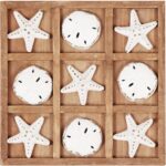 A distressed white NIKKY HOME Beach Tic Tac Toe game board with starfish and sand dollar resin pieces.