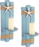 Two blue wooden starfish wall candle sconces with hemp rope accents, holding small candles, mounted against a light wall.